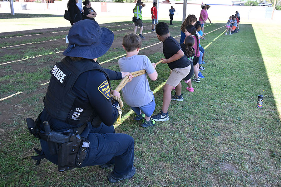 Students play tug of water with a Tucson Police officer