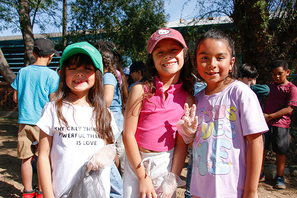 Three girls smile in the school courtyard