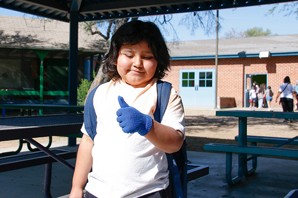A little boy gives a thumbs-up in his blue glove